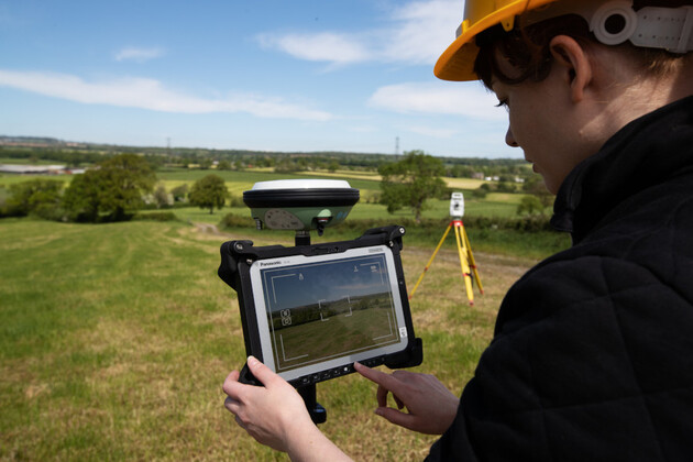 Frau auf Feld hält Toughbook in der Hand