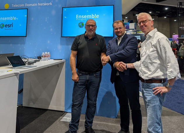 Drei Männer geben sich auf einem Messestand die Hand