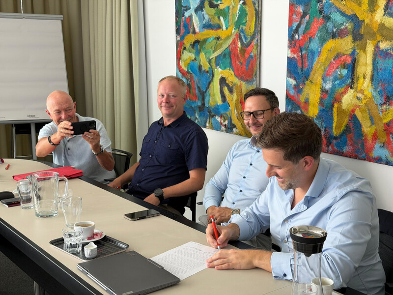 Herren an einem Schreibtisch unterschreiben Dokument