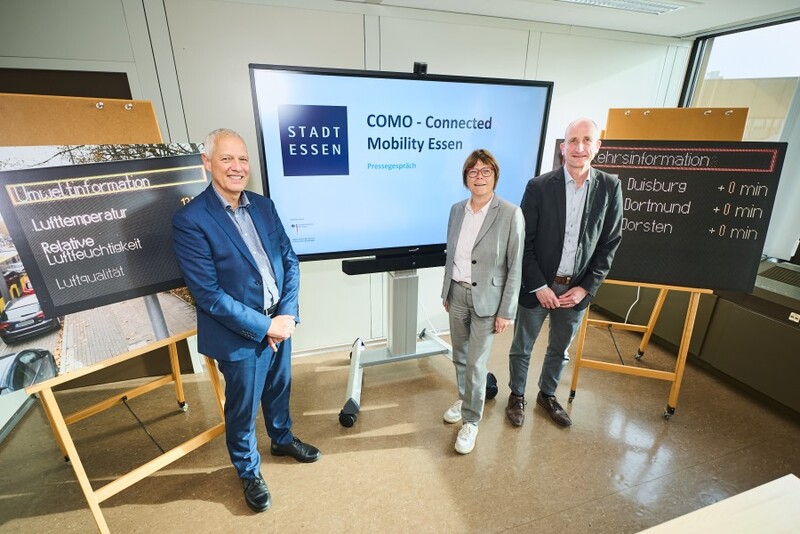 Drei Personen stehen vor Monitor